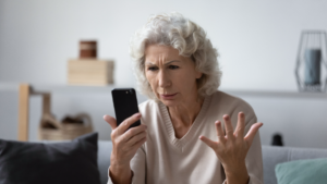 Flustered older caucasian woman with smartphone